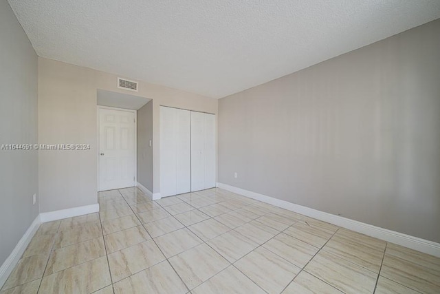 unfurnished bedroom with light tile patterned floors, a closet, and a textured ceiling