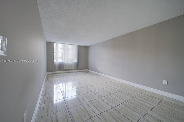 tiled spare room featuring a textured ceiling