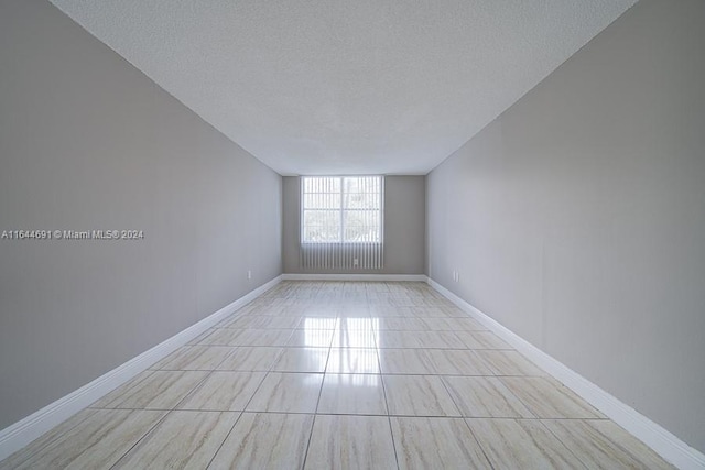 spare room with a textured ceiling and light tile patterned flooring