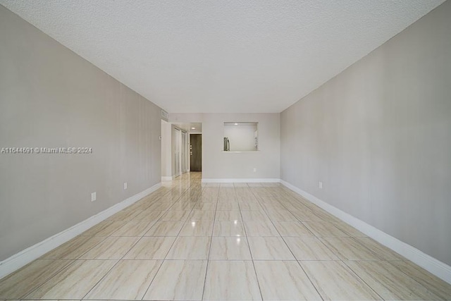 tiled empty room with a textured ceiling