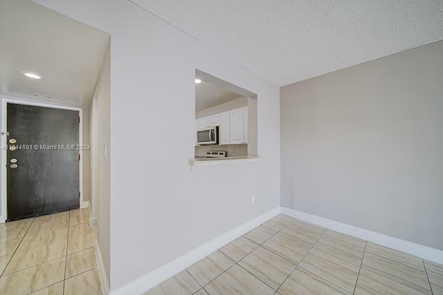 corridor featuring a textured ceiling and light tile patterned flooring