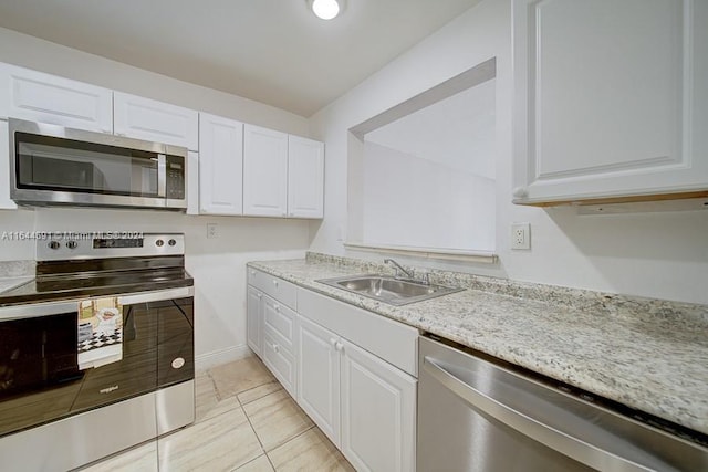 kitchen featuring stainless steel appliances, white cabinetry, sink, light stone countertops, and light tile patterned floors