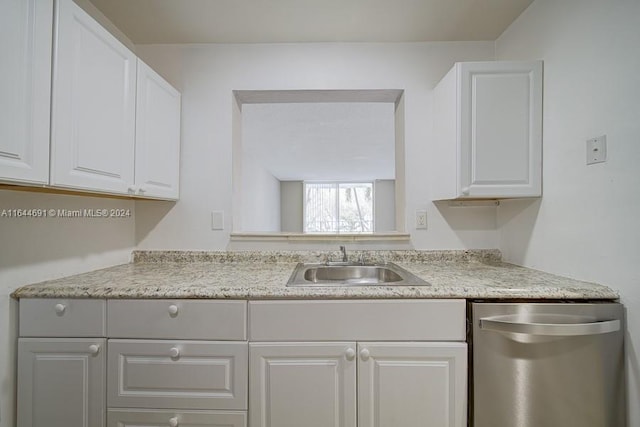 kitchen featuring white cabinets, stainless steel dishwasher, sink, and light stone counters