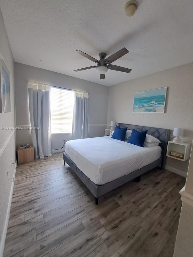 bedroom with ceiling fan, a textured ceiling, and wood-type flooring