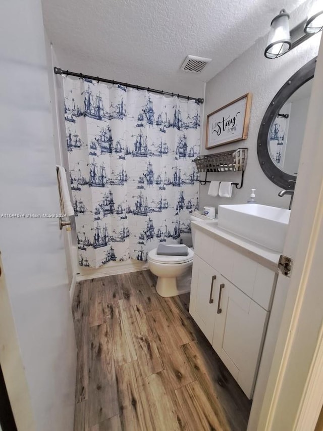 bathroom with toilet, a textured ceiling, vanity, and wood-type flooring