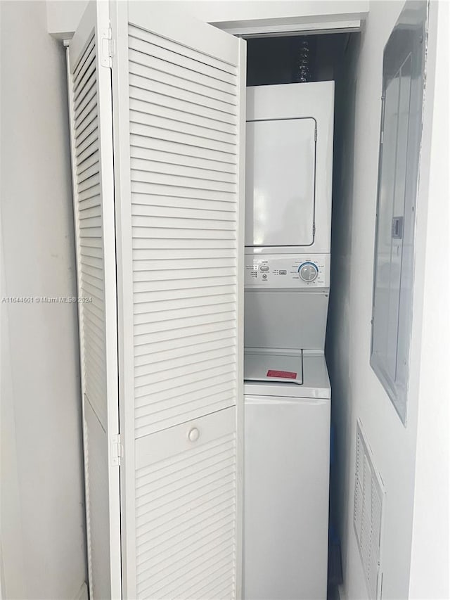 clothes washing area featuring stacked washer and dryer and electric panel