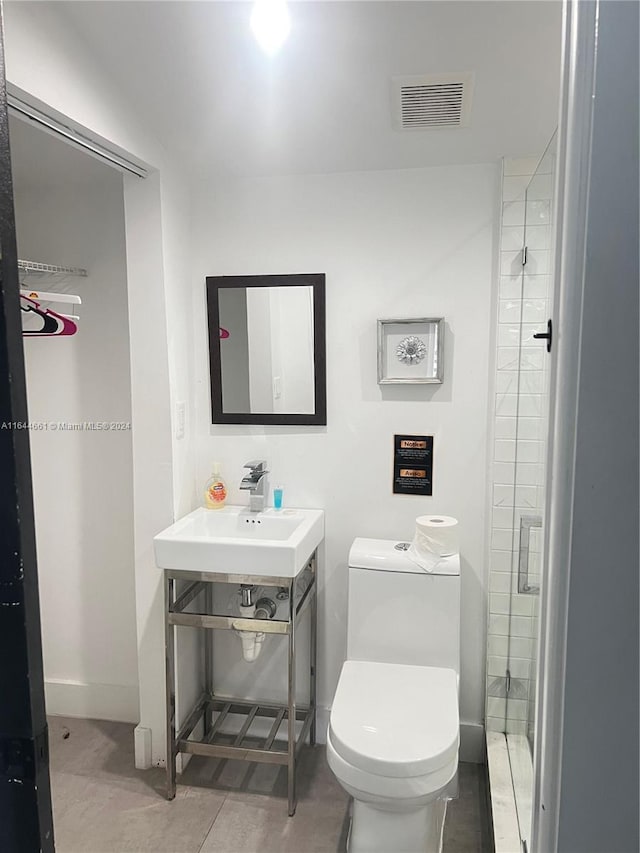 bathroom featuring a shower with door, toilet, vanity, and tile patterned floors