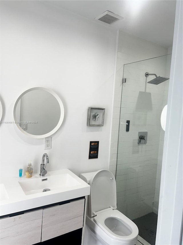 bathroom featuring a tile shower, vanity, and toilet