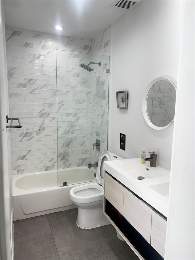 full bathroom with tile patterned flooring, tiled shower / bath, vanity, and toilet