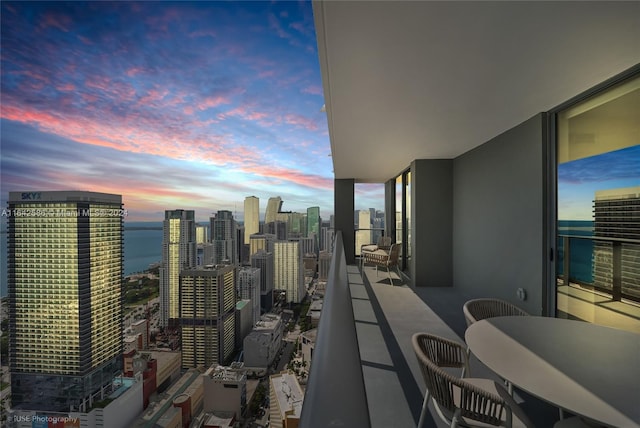 balcony at dusk featuring a water view