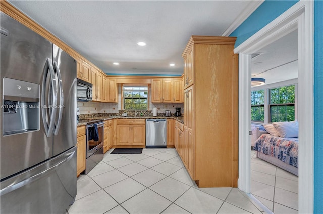 kitchen with backsplash, dark stone countertops, appliances with stainless steel finishes, light tile patterned floors, and crown molding