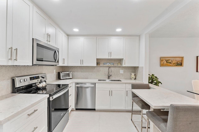 kitchen featuring light tile patterned floors, stainless steel appliances, white cabinetry, and sink