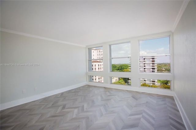 empty room featuring a wealth of natural light, parquet flooring, and crown molding