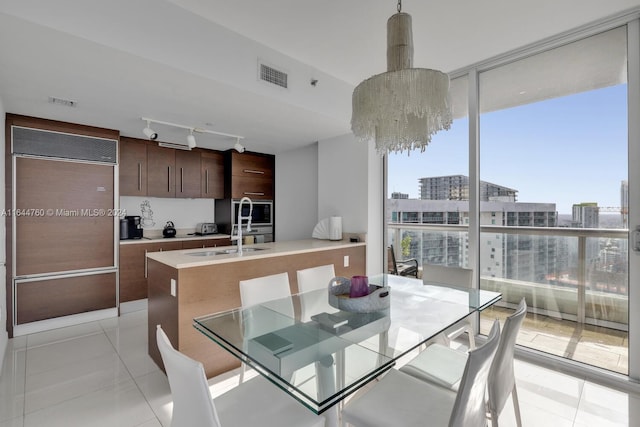 dining area with visible vents, expansive windows, light tile patterned flooring, rail lighting, and a chandelier