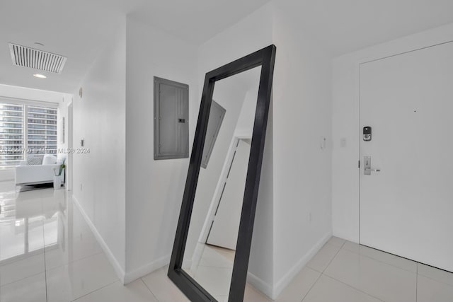 hall with electric panel, visible vents, baseboards, and tile patterned flooring