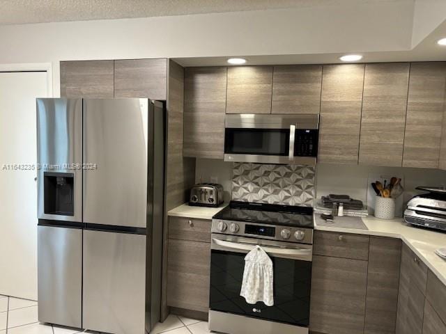 kitchen with light tile patterned flooring, backsplash, and stainless steel appliances