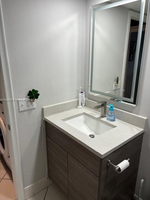 bathroom featuring tile patterned flooring, vanity, and washer / clothes dryer