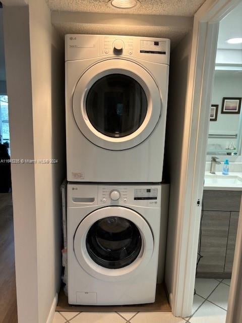 washroom with sink, stacked washing maching and dryer, and light tile patterned floors