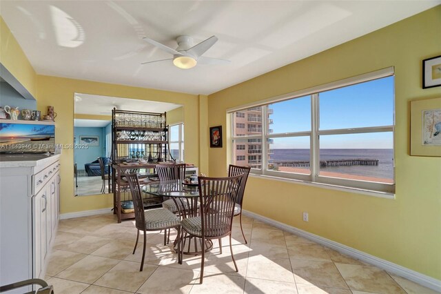 tiled dining space with ceiling fan, a water view, and plenty of natural light