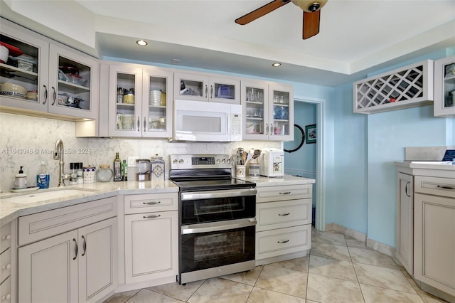 kitchen featuring double oven range, a sink, decorative backsplash, and white microwave