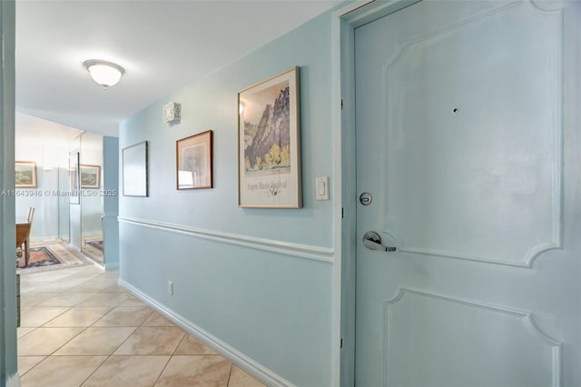 hall featuring light tile patterned floors and baseboards