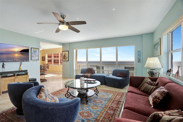 living room featuring ceiling fan, a water view, and light tile patterned flooring