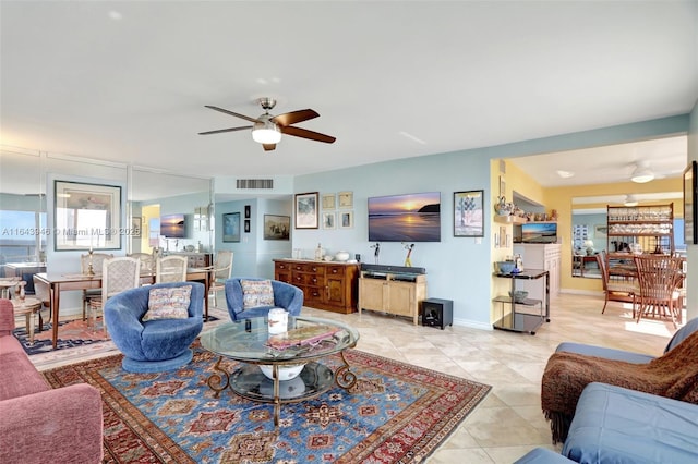 living area featuring light tile patterned floors, visible vents, baseboards, and a ceiling fan