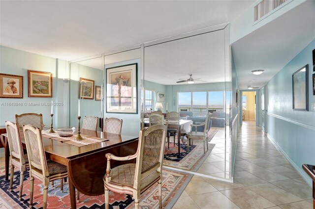 tiled living room with ceiling fan and a water view