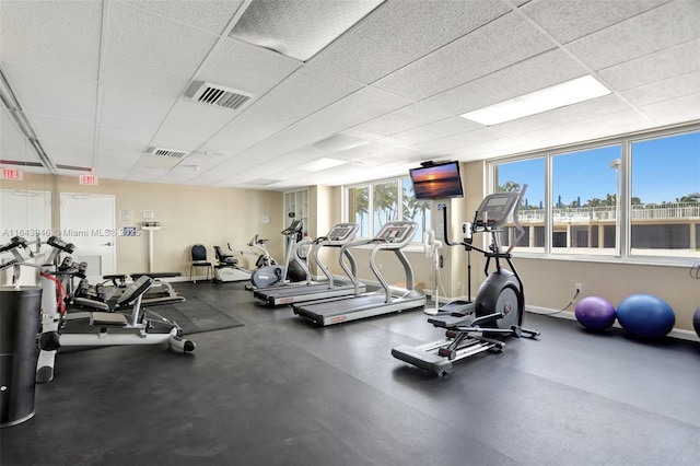 workout area with a paneled ceiling, visible vents, and baseboards