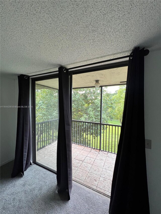 entryway with a wealth of natural light, light carpet, and a textured ceiling