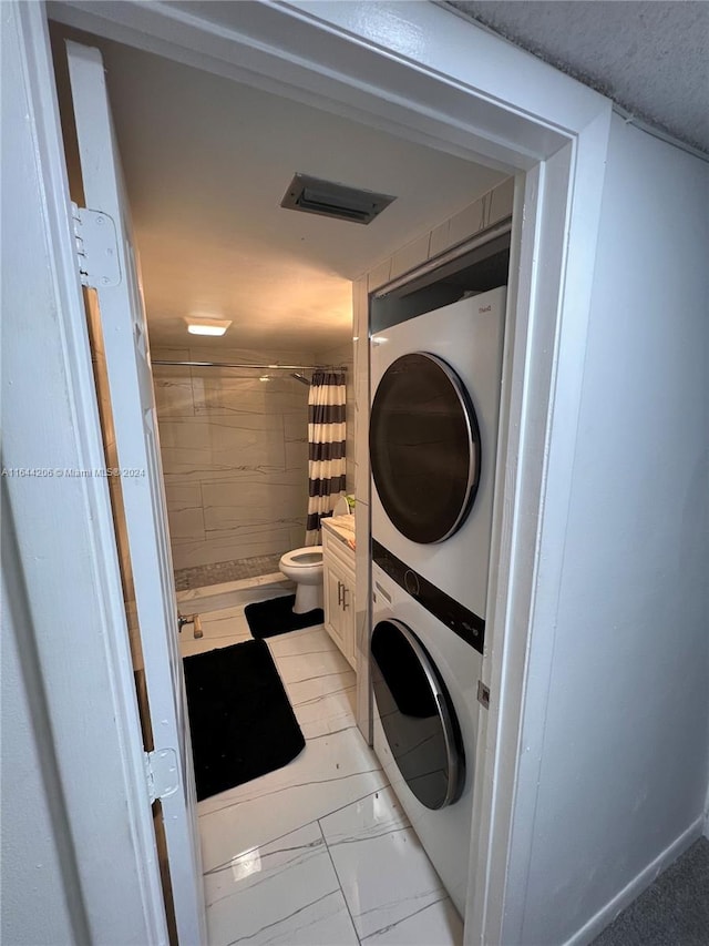 clothes washing area with light tile patterned floors and stacked washer and dryer