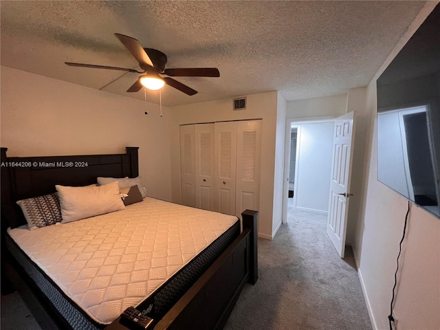 carpeted bedroom featuring a textured ceiling, a closet, and ceiling fan