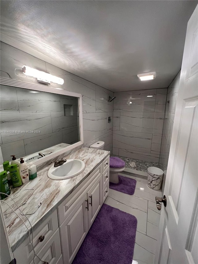 bathroom featuring tiled shower, toilet, tile patterned flooring, and vanity