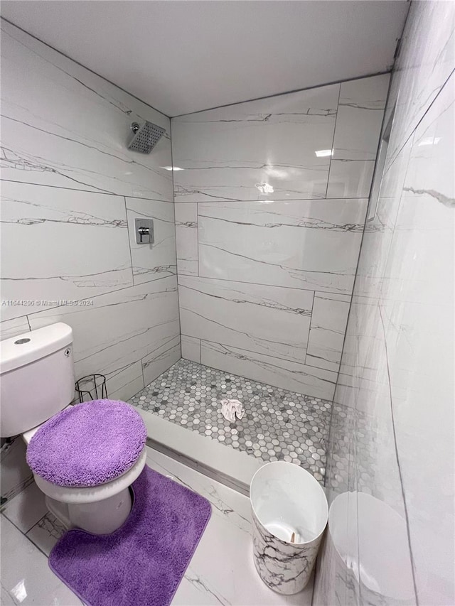 bathroom featuring tile patterned flooring, tiled shower, and toilet