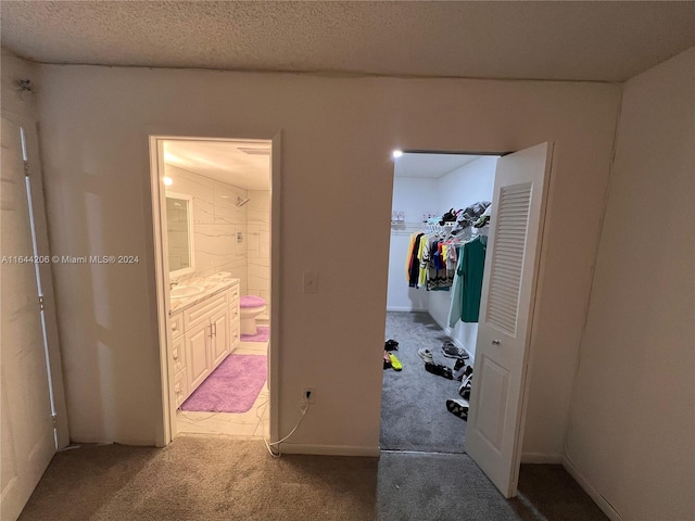 carpeted bedroom with sink, a closet, a textured ceiling, and connected bathroom