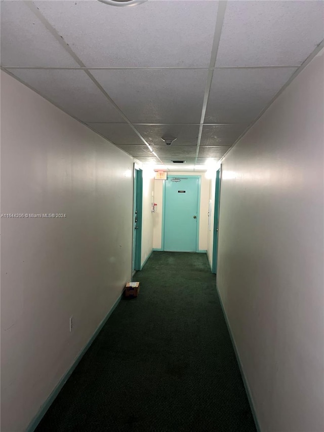 corridor with dark carpet and a paneled ceiling