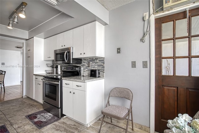 kitchen featuring appliances with stainless steel finishes, tasteful backsplash, tile patterned flooring, and white cabinets