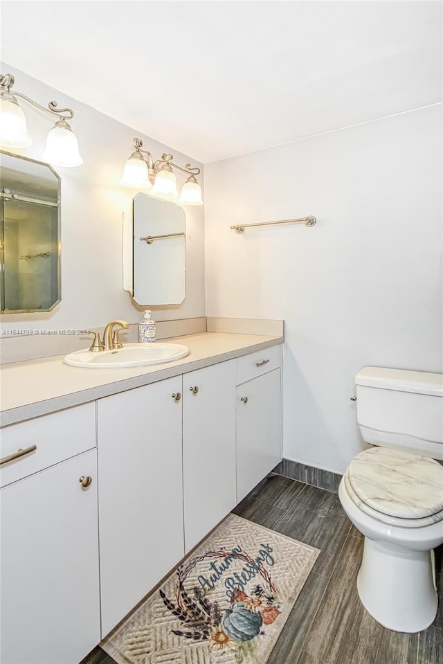 bathroom with wood-type flooring, toilet, and vanity