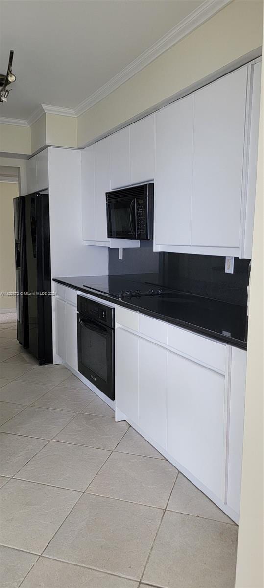 kitchen with black appliances, light tile patterned flooring, white cabinetry, and ornamental molding