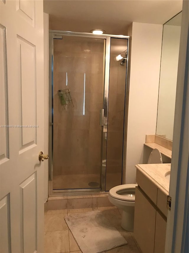 bathroom featuring tile patterned flooring, an enclosed shower, vanity, and toilet