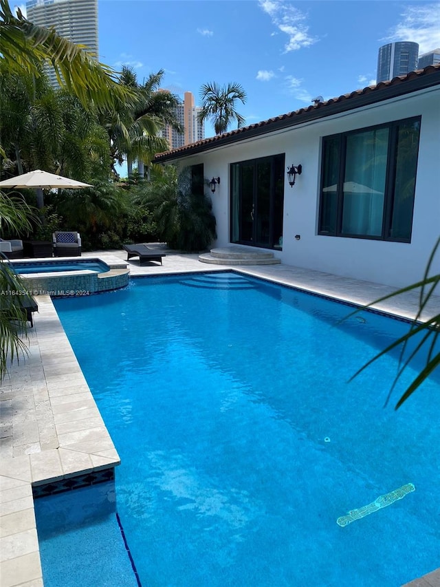 view of swimming pool with central AC unit, a patio area, and an in ground hot tub