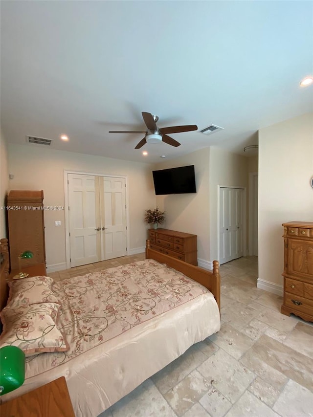 bedroom with ceiling fan, light tile patterned floors, and two closets