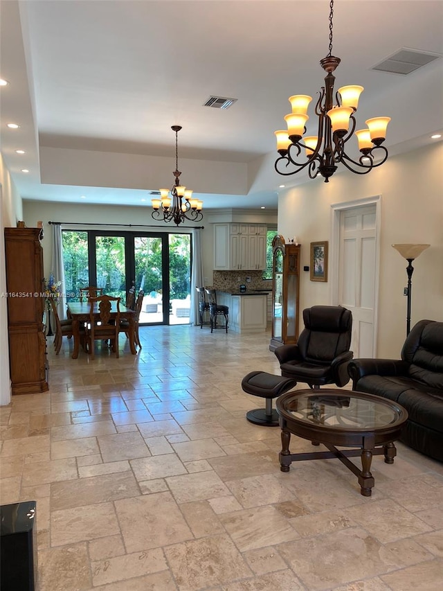 living room with a raised ceiling, a notable chandelier, and light tile patterned flooring