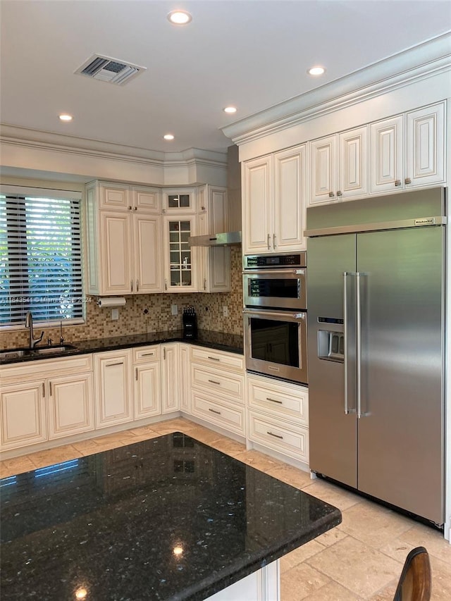 kitchen with dark stone countertops, light tile patterned floors, stainless steel appliances, sink, and decorative backsplash