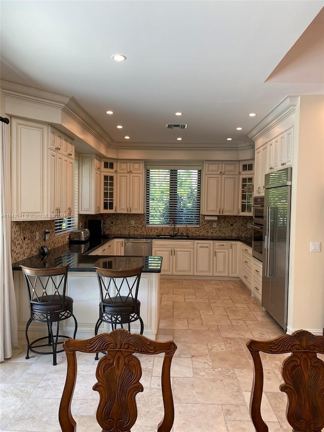 kitchen featuring backsplash, kitchen peninsula, appliances with stainless steel finishes, and cream cabinetry