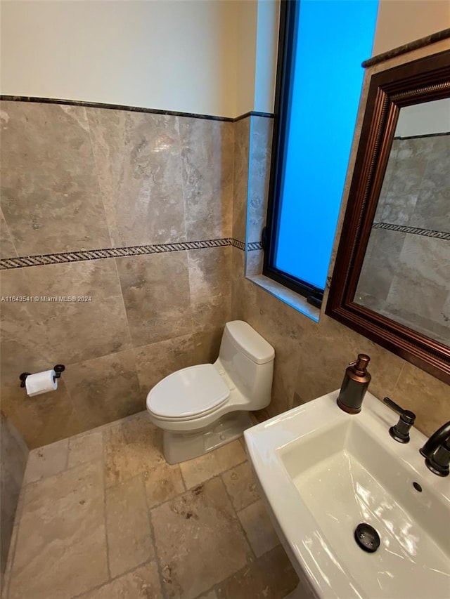 bathroom featuring tile walls, tile patterned flooring, toilet, and sink