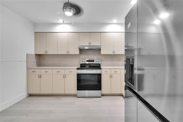 kitchen featuring appliances with stainless steel finishes, light hardwood / wood-style flooring, decorative backsplash, cream cabinets, and ceiling fan