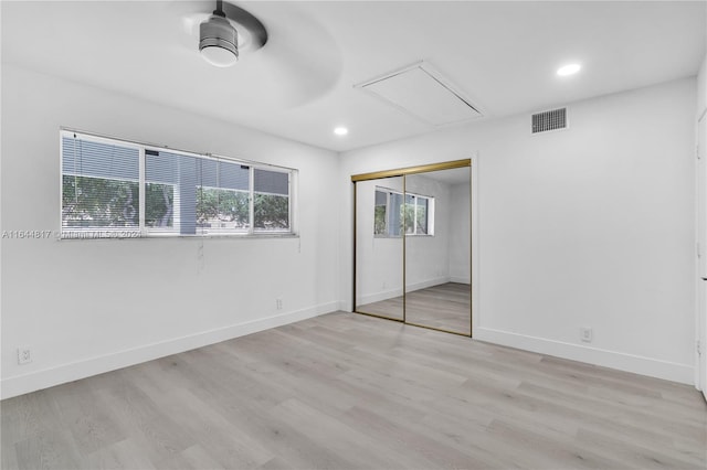 unfurnished bedroom featuring multiple windows, a closet, and light wood-type flooring