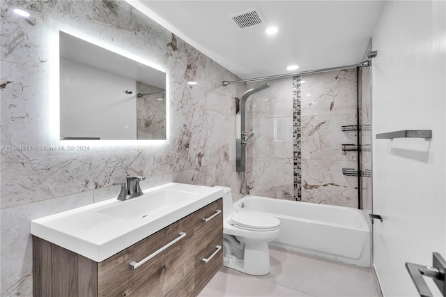 full bathroom featuring tiled shower / bath, tile walls, tile patterned flooring, vanity, and toilet