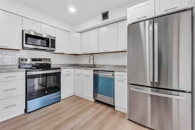 kitchen with sink, white cabinets, light hardwood / wood-style flooring, and stainless steel appliances